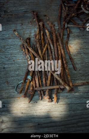 Beaucoup de vieux clous rouillés tordus couché sur une planche en bois. Banque D'Images