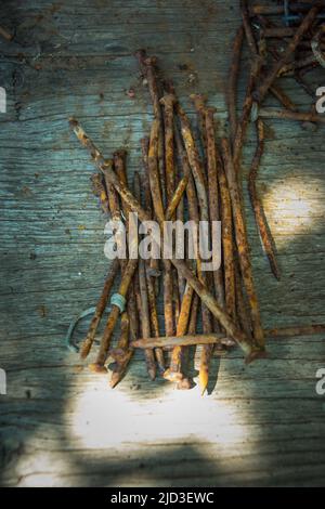 Beaucoup de vieux clous rouillés tordus couché sur une planche en bois. Banque D'Images