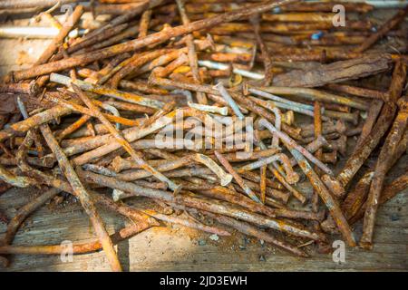 Beaucoup de vieux clous rouillés tordus couché sur une planche en bois. Banque D'Images