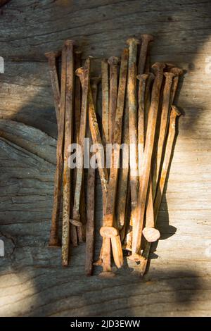 Beaucoup de vieux clous rouillés tordus couché sur une planche en bois. Banque D'Images