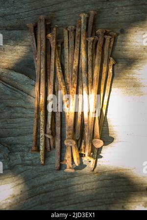 Beaucoup de vieux clous rouillés tordus couché sur une planche en bois. Banque D'Images