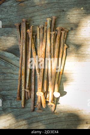 Beaucoup de vieux clous rouillés tordus couché sur une planche en bois. Banque D'Images