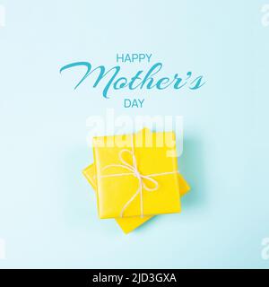 Carte de voeux pour la fête des mères. Boîtes-cadeaux carrées jaunes sur fond bleu. Pose à plat Banque D'Images