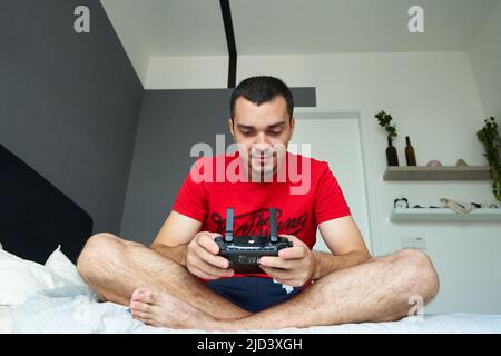 Guy joue avec un nouveau drone dans sa chambre. Kuala Lumpur, Malaisie - 04.06.2020 Banque D'Images