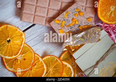 Tranches de barres de chocolat orange et rose séchées sur fond de bois. Photo de haute qualité. Concept de vacances, Saint-Valentin. Banque D'Images