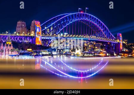 Le pont du port de Sydney se reflète dans la pierre polie des quais du traversier circulaire au spectacle lumineux Vivid Sydney 2022. Banque D'Images