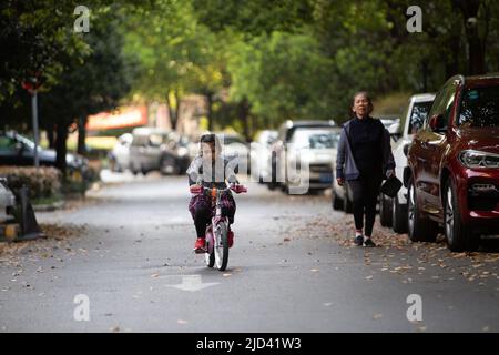 Une fille indonésienne et sa grand-mère vêtues d'un thème de printemps, un vélo BTWIN rose au printemps, dans la rue d'un complexe d'appartements à Shanghai Banque D'Images