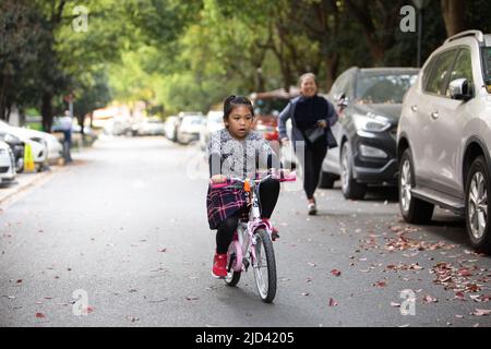 Une fille indonésienne et sa grand-mère vêtues d'un thème de printemps, un vélo BTWIN rose au printemps, dans la rue d'un complexe d'appartements à Shanghai Banque D'Images