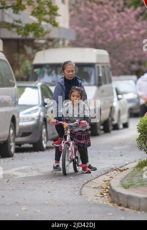 Une fille indonésienne et sa grand-mère vêtues d'un thème de printemps, un vélo BTWIN rose au printemps, dans la rue d'un complexe d'appartements à Shanghai Banque D'Images