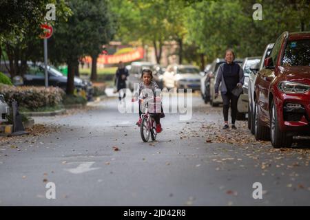 Une fille indonésienne et sa grand-mère vêtues d'un thème de printemps, un vélo BTWIN rose au printemps, dans la rue d'un complexe d'appartements à Shanghai Banque D'Images