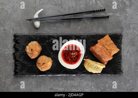 DIM sum Gyozas Asian Fried dumplings Party Set dans Black Slate plaque céramique sur fond gris. Flat Lay, Copy Space Banque D'Images