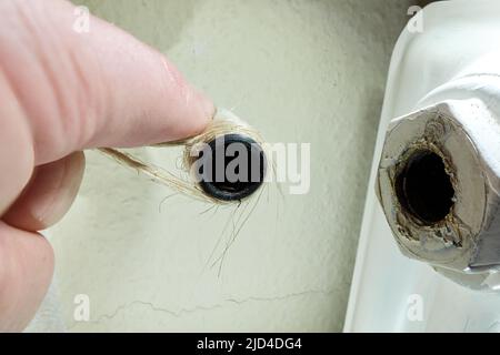 Sceller le tuyau de chauffage avec du chanvre. Remplacer la soupape thermostatique du chauffage du radiateur. Raccord à vis réparé à la main lors de l'installation. Banque D'Images