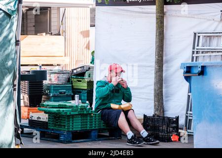 Epsom Surrey, Londres, 11 juin 2022, homme assis seul manger un hamburger portant une casquette de baseball rouge Banque D'Images