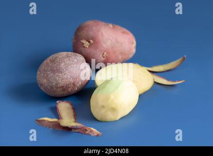 Gros plan de pommes de terre rouges pelées et crues sur une table bleue. Régime végétarien. Glucides. Composition minimale Banque D'Images