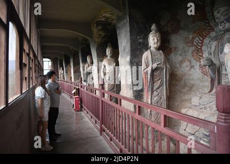 Tianshui, province chinoise de Gansu. 9th juin 2022. Les touristes visitent les grottes de Maijishan dans la ville de Tianshui, dans le nord-ouest de la Chine, province de Gansu, 9 juin 2022. Les grottes de Maijishan, âgées de plus de 1 600 ans, sont sculptées dans les grottes d'un pic isolé de la montagne sur l'ancienne route de la soie dans la ville de Tianshui. Crédit : Chen Bin/Xinhua/Alay Live News Banque D'Images