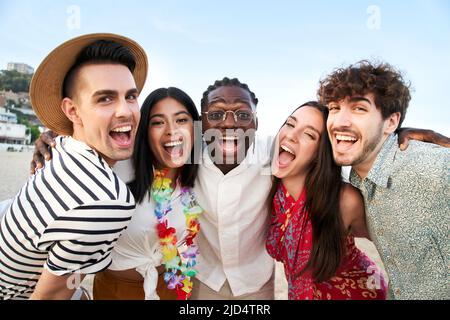 Portrait regardant l'appareil photo d'un cinq amis souriants appréciant les vacances d'été. Groupe de personnes appréciant l'amitié sur la plage. Les jeunes hommes et Banque D'Images