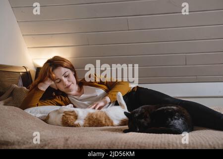 Femme d'âge moyen tenant un chat au gingembre mignon. Femme embrassant son joli petit chaton dans la chambre le soir. Copier l'espace. Adorable animal domestique Banque D'Images