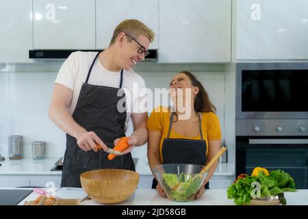 Couple romantique cuisine dans la cuisine. Un homme charmant et une femme charmante s'amusent ensemble tout en faisant des idées saines de mode de vie salade. Banque D'Images