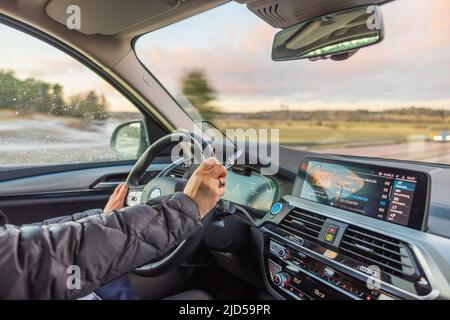 Gros plan des mains de la femme sur le volant de la BMW IX3. Suède. Banque D'Images
