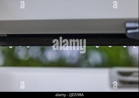 Chutes de gouttes de pluie du cadre de la fenêtre du puits de lumière sous la pluie. Banque D'Images