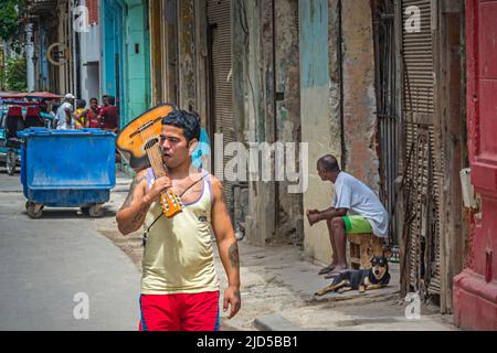 Le jeune homme marche avec une guitare sur son épaule dans les rues de la vieille Havane, Cuba Banque D'Images