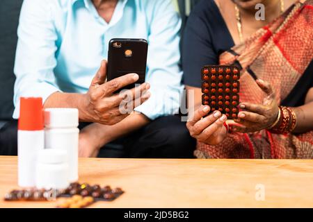 gros plan sur un vieux couple senior qui commande des médicaments sur téléphone portable depuis son domicile - concept de soins de santé, de technologie et d'e-commerce Banque D'Images