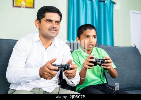 Père et fils jouant au jeu vidéo en utilisant le bloc de jeu à la maison pendant les vacances de week-end - concept de divertissement, de collage et de style de vie de loisirs Banque D'Images