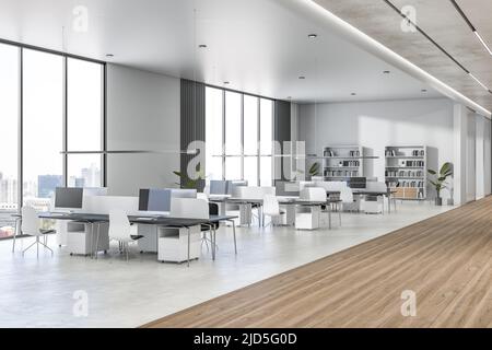 Vue latérale sur le bureau spacieux de collègue avec plafond et murs très lumineux, sol en bois et béton glacé, vue sur la ville depuis de grandes fenêtres et des œuvres blanches Banque D'Images