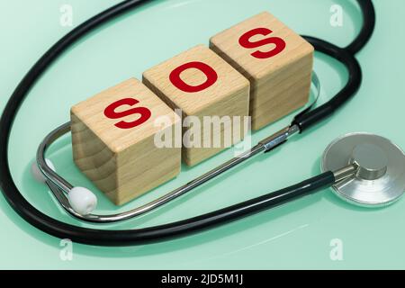 Inscription SOS rouge sur blocs de bois et stéthoscope médical, concept de santé Banque D'Images