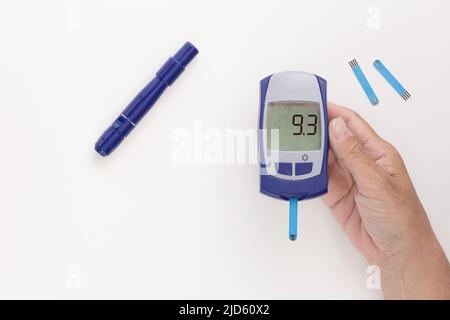 Vue de dessus d'une femme en culture tenant le glucomètre à la main avec neuf points trois 9,3 mmol par litre d'indice glycémique sur l'affichage avec une bandelette de test à l'intérieur, l Banque D'Images