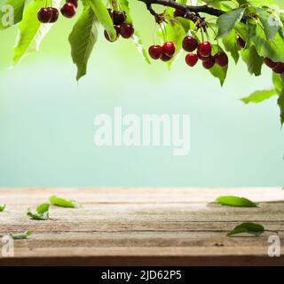 Cerisier sur une ancienne table de jardin en bois. Table vide avec cerises mûres rouges. Pour le placement des produits alimentaires et des boissons Banque D'Images