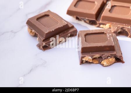 QUATRE MORCEAUX DE CHOCOLAT NOIR SUR UNE TABLE EN MARBRE BLANC. COULEUR. Banque D'Images