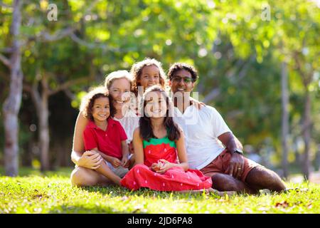 Promenade en famille dans le parc d'été. Parents et enfants à l'extérieur. Mère, père et enfants jouent, rient, pique-nique dans un jardin ensoleillé. Banque D'Images