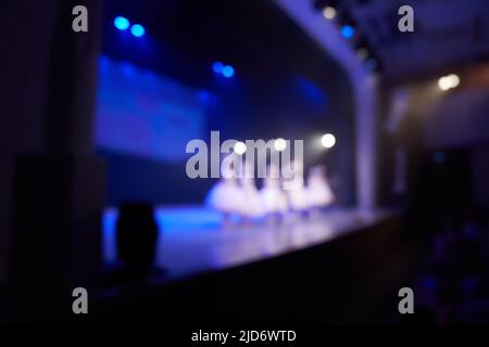 Arrière-plan flou d'une scène de danse avec un groupe de petites filles en robes blanches. Éclairage de scène lumineux. Silhouettes de petits danseurs. Photo de haute qualité Banque D'Images