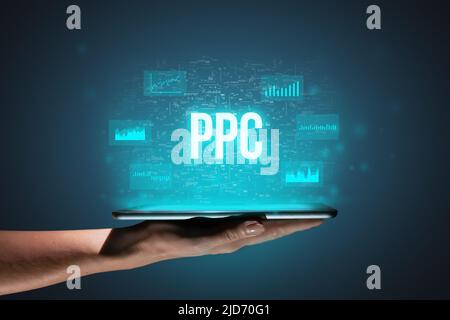 Concept PPC ou paiement par clic. Acronyme commercial. Icônes holographiques et texte sur tablette entre les mains. Banque D'Images