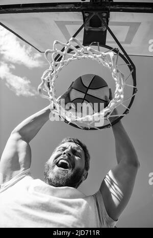 homme joueur réussi lancer ballon de basket-ball à travers le panier, succès Banque D'Images