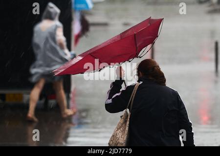 Bucarest, Roumanie - 17 juin 2022 : les gens traversent la rue sous une forte pluie. Banque D'Images