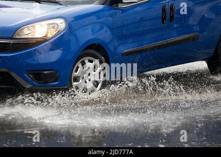 Bucarest, Roumanie - 17 juin 2022: Une voiture accélère à travers une flaque lors d'une forte pluie. Banque D'Images