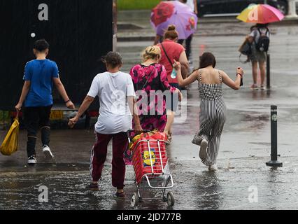 Bucarest, Roumanie - 17 juin 2022 : les gens traversent la rue sous une forte pluie. Banque D'Images