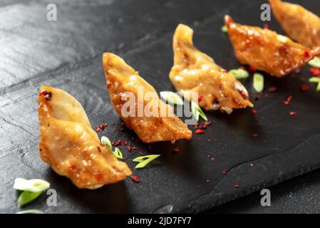 Beignets asiatiques gyoza ou Jiaozi à la sauce soja, et oignons verts sur fond Banque D'Images