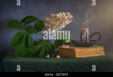 Fleurs de châtaignier sur une branche avec des feuilles et une bougie éteinte. Matin. Banque D'Images