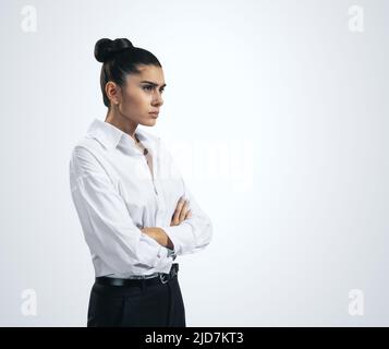 Ressentiment et émotions désagréables concept avec la jeune femme stressée en chemise blanche croisant ses bras isolés sur fond gris clair, gros plan Banque D'Images