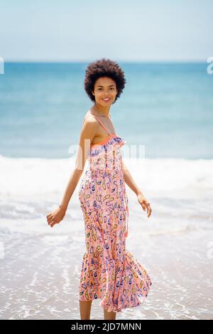 Femme noire élégante sur une plage de sable Banque D'Images