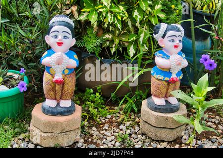 Ornements de jardin thaïlandais traditionnels : statuettes de filles souriantes dans une posture accueillante Banque D'Images