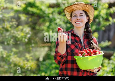 portrait d'une jeune femme paysanne souriante avec des fraises dans un bol Banque D'Images