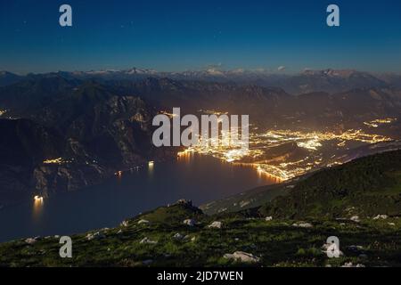 Lumière de lune sur le lac de Garde depuis le sommet du mont Altissimo di Nago. Lumières nocturnes de la ville de Riva del Garda. Trentin. Prealpi Gardesane. Italie. Banque D'Images