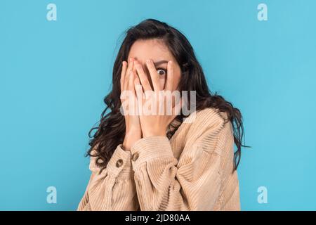 Effrayée millénaire caucasienne femme brunette étudiant en décontracté couvre son visage avec les mains Banque D'Images