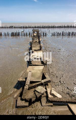 Un sentier en béton démoli sur des piliers au bout du chemin avec l'horizon de la mer. Banque D'Images