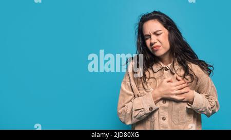 Une femme blanche millennale déjumelée, brunette, appuie les mains sur la poitrine, souffrant de douleurs cardiaques Banque D'Images