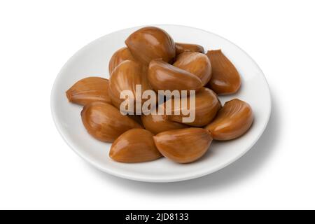 Assiette avec gousses d'ail marinées savoureuses, Nowruz, isolée sur fond blanc de gros plan Banque D'Images